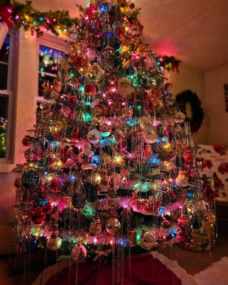 90s Christmas Tree Decor: 8 Ideas for Retro Holiday Charm 7 A decorated Christmas tree with colorful lights, various ornaments, and long hanging tinsel strands.