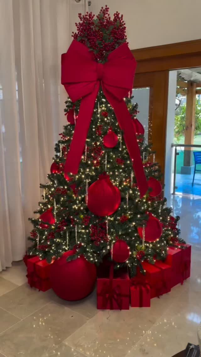 All Red Christmas Tree Decorations: 7 Ideas for Monochrome Style 6 A Christmas tree decorated with red ornaments, warm lights, and a large red bow topper.