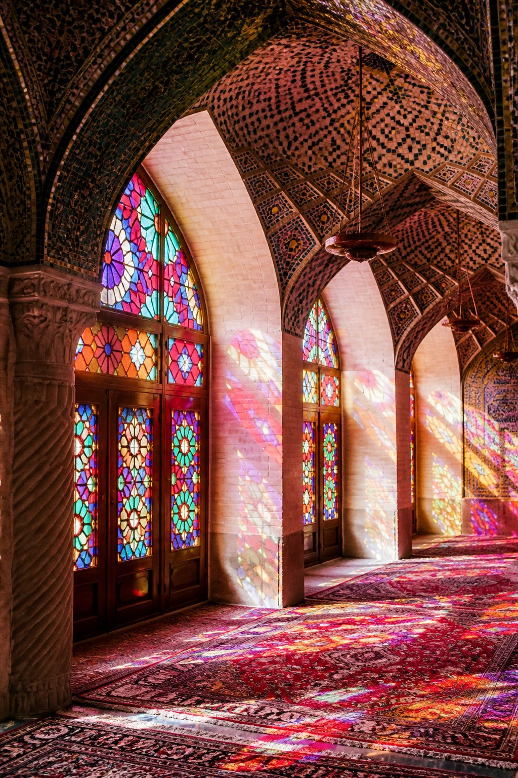 Beautiful Stained Glass Windows: 14 Sites That Changed Light Forever 3 Stained glass windows of Nasir al-Mulk Mosque creating a pink-hued prayer hall.