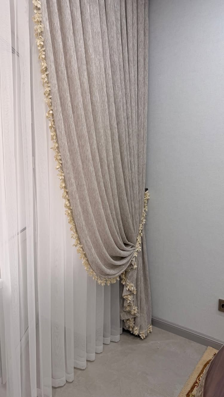 10 Bedroom Window Decor Ideas for Every Wall Height 9 Beige tassel-trimmed curtains draped over white sheer curtains against a white wall.