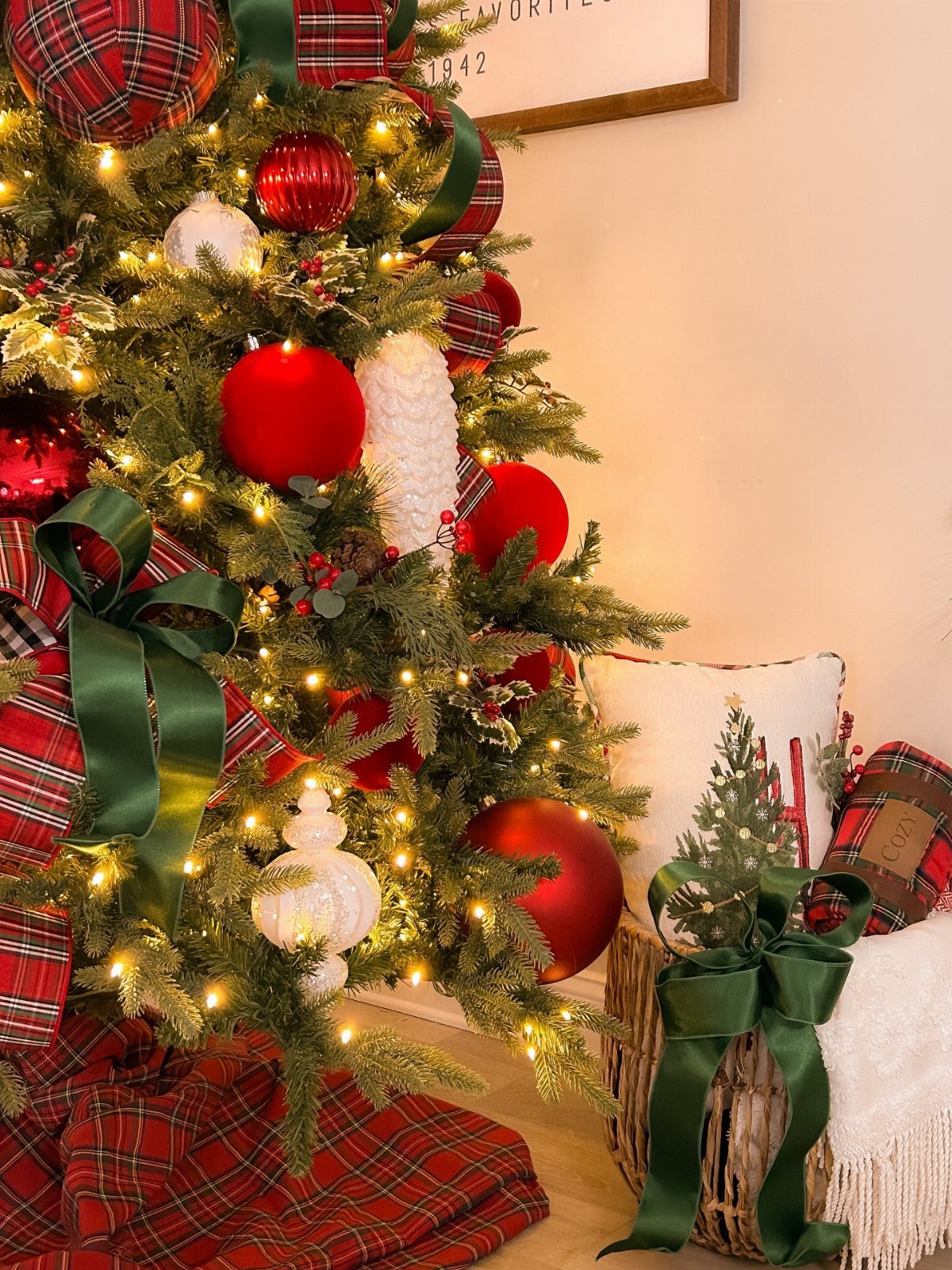 25 Christmas Decor Apartment Ideas That Maximize Space 5 Decorated Christmas tree with red ornaments and green ribbons next to a festive basket.