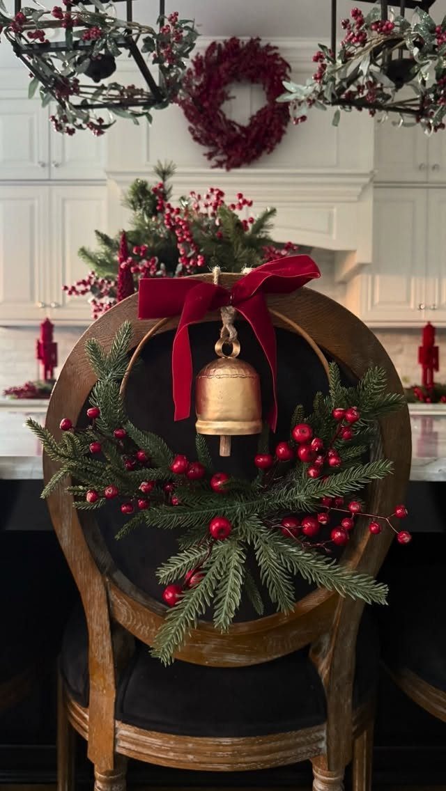 25 Christmas Decor Apartment Ideas That Maximize Space 18 A wooden chair decorated with evergreen branches, red berries, and a gold bell with a red bow.