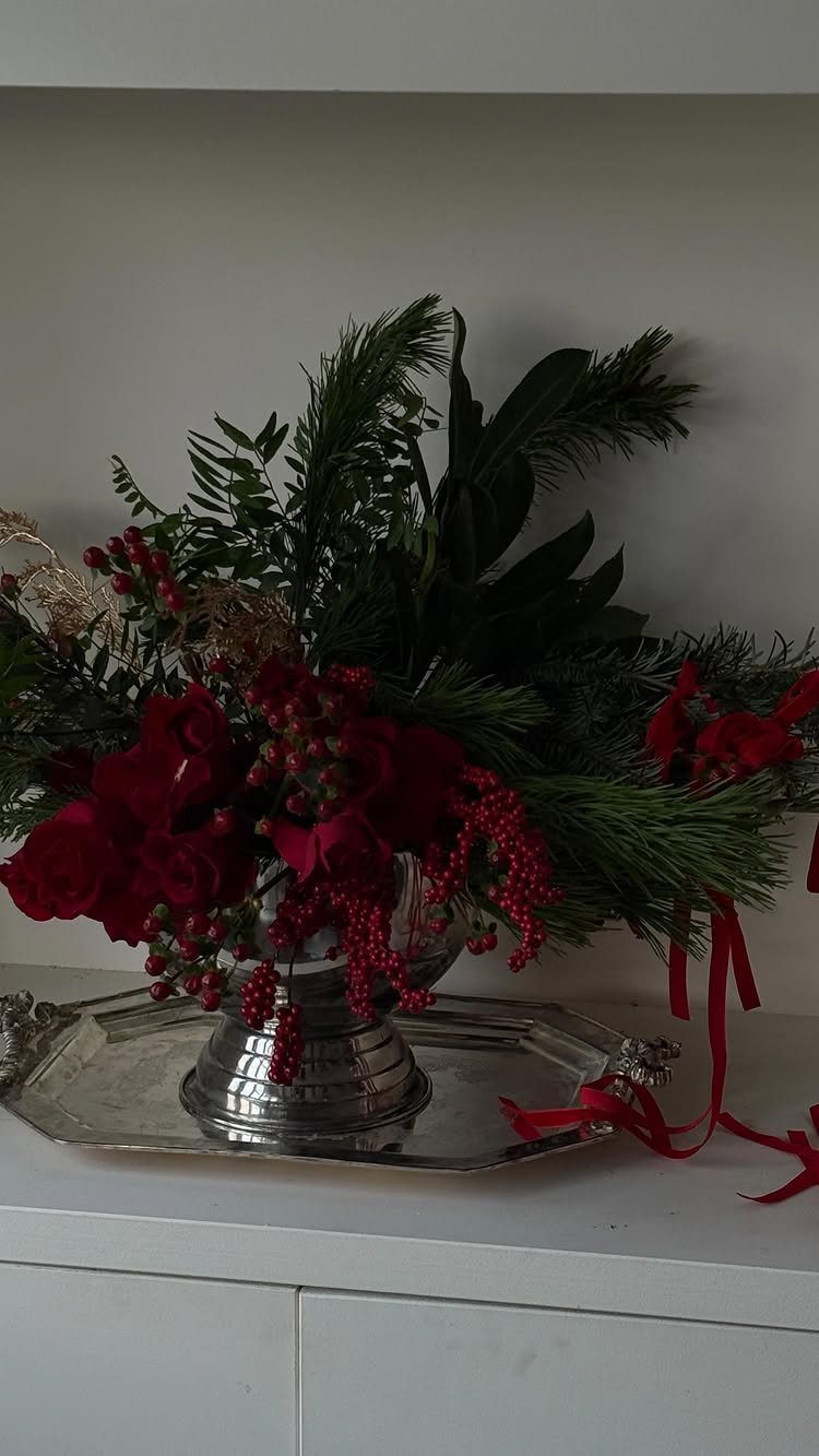 25 Christmas Decor Apartment Ideas That Maximize Space 9 Red roses and berries with green pine branches in a silver vase on a tray.