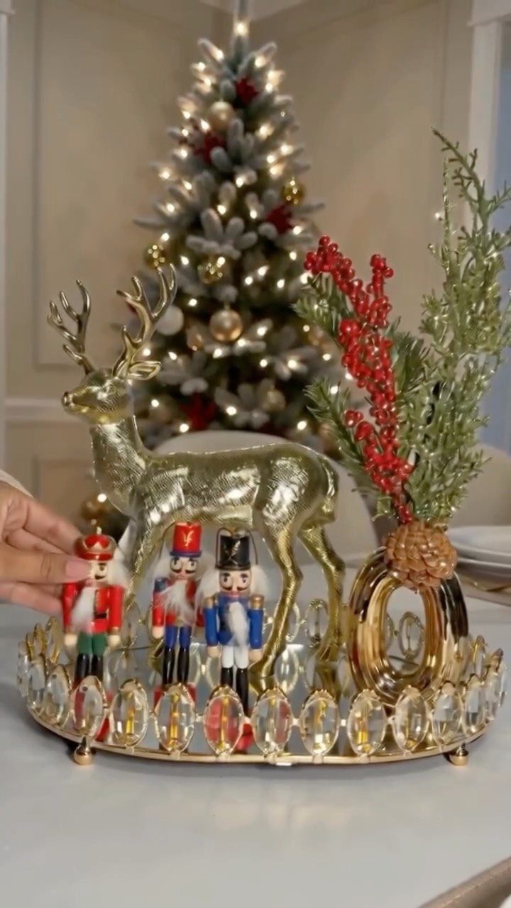 25 Christmas Decor Apartment Ideas That Maximize Space 4 A gold tray holding a reindeer, nutcrackers, and red berries with a Christmas tree background.