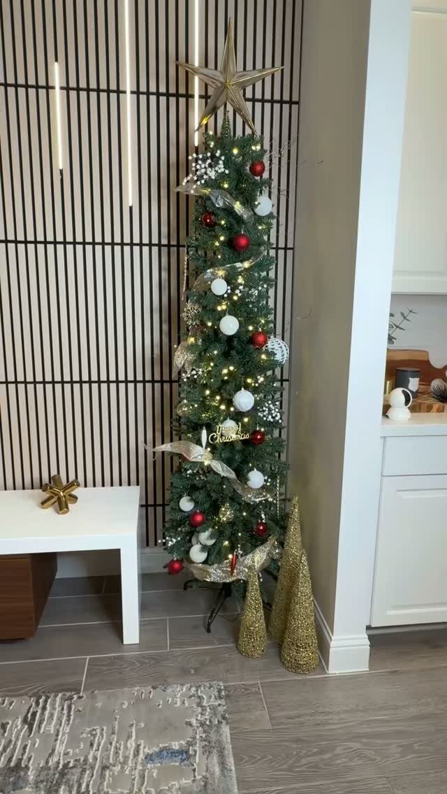 25 Christmas Decor Apartment Ideas That Maximize Space 10 A slim decorated Christmas tree with red and white ornaments standing in a modern room corner.
