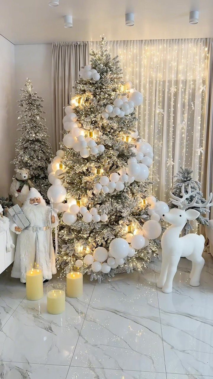 21 Christmas Decor Inspiration Ideas for Your Whole Home 2026 1 A silver Christmas tree decorated with white ornaments and warm lights surrounded by white holiday figurines.