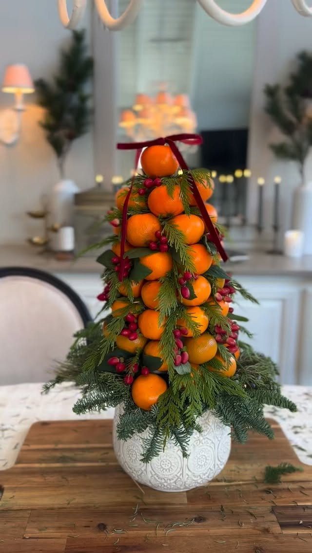 21 Christmas Decor Inspiration Ideas for Your Whole Home 2026 17 A conical centerpiece composed of whole oranges, green foliage, and red berries in a white bowl.