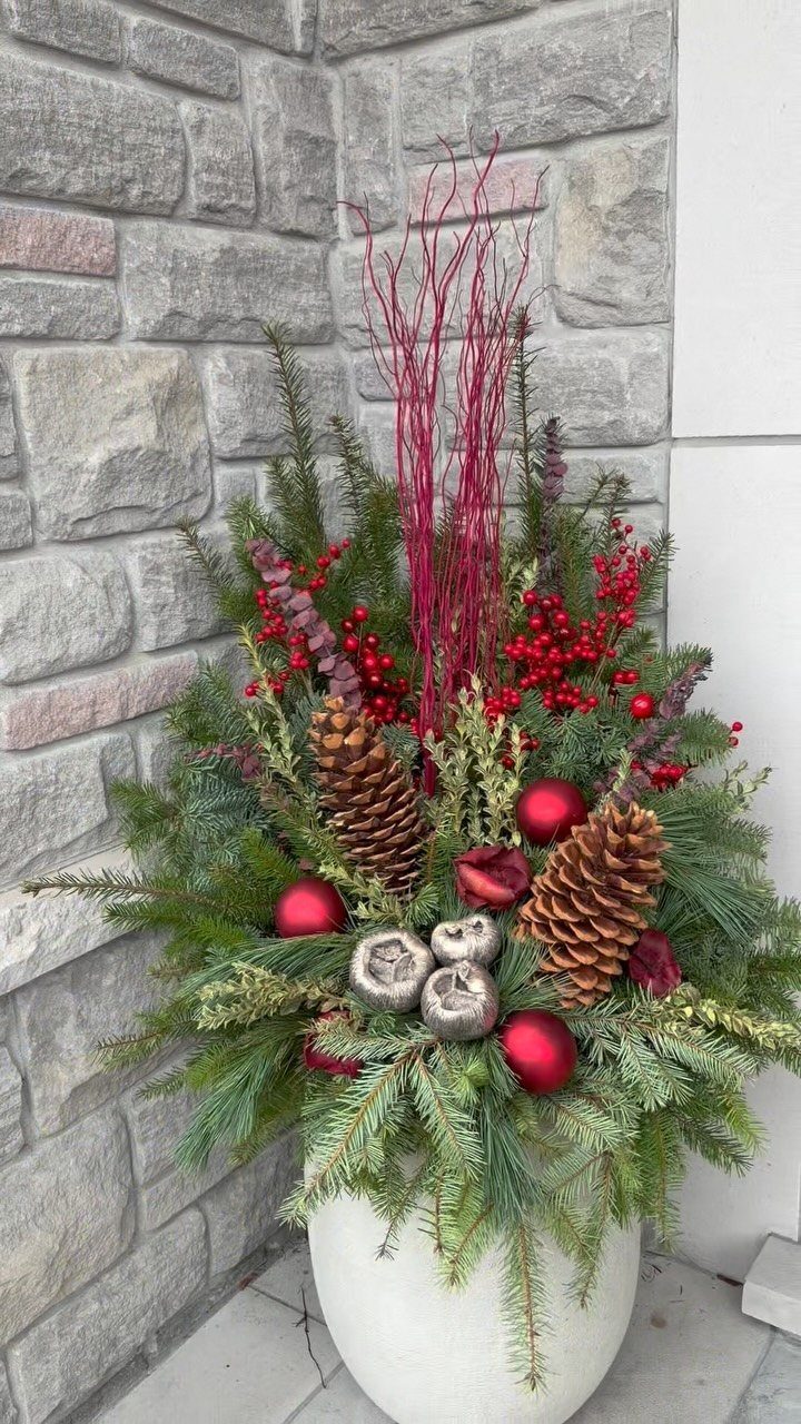 21 Christmas Decor Inspiration Ideas for Your Whole Home 2026 16 Holiday planter with evergreen branches, red berries, pinecones, and red ornaments in a white pot.
