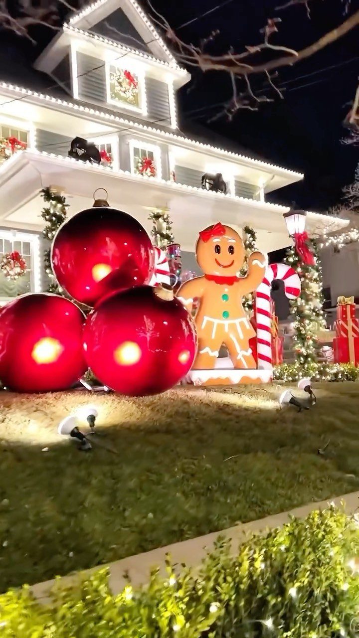 21 Christmas Decor Inspiration Ideas for Your Whole Home 2026 21 Large red ornament decorations and a gingerbread man figure on a lawn in front of a lit house.