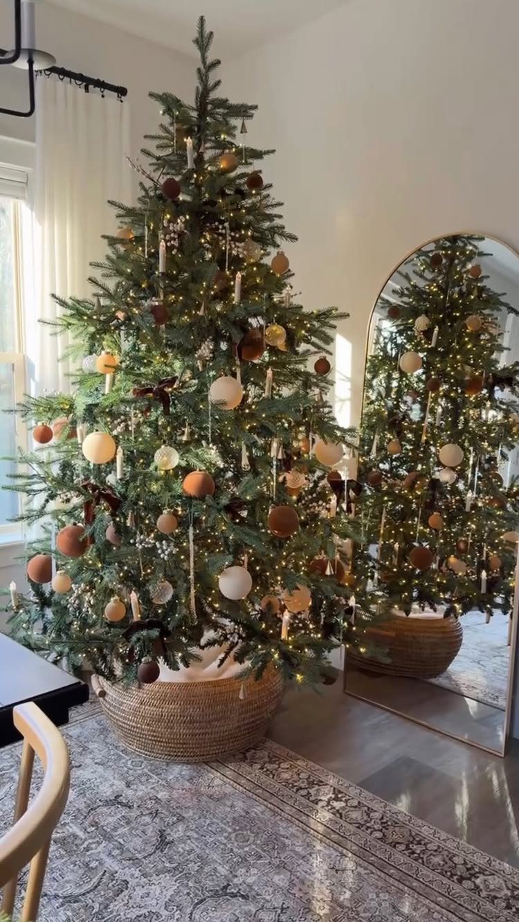 11 Christmas Home Decorating Ideas for 2026: Garlands to Lanterns 4 A decorated Christmas tree with warm lights and neutral ornaments sitting in a woven basket.