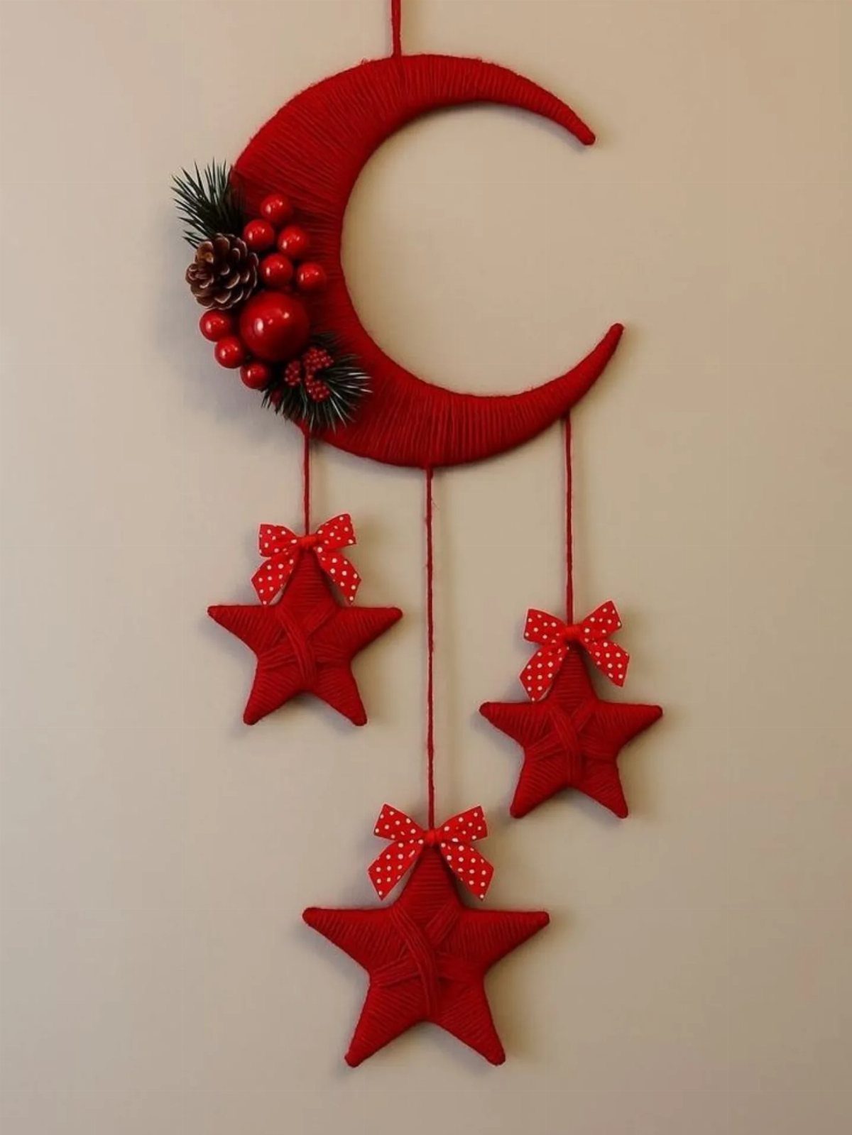 11 Christmas Home Decorating Ideas for 2026: Garlands to Lanterns 11 Red crescent moon and hanging fabric stars decorated with berries and pinecones on a wall.