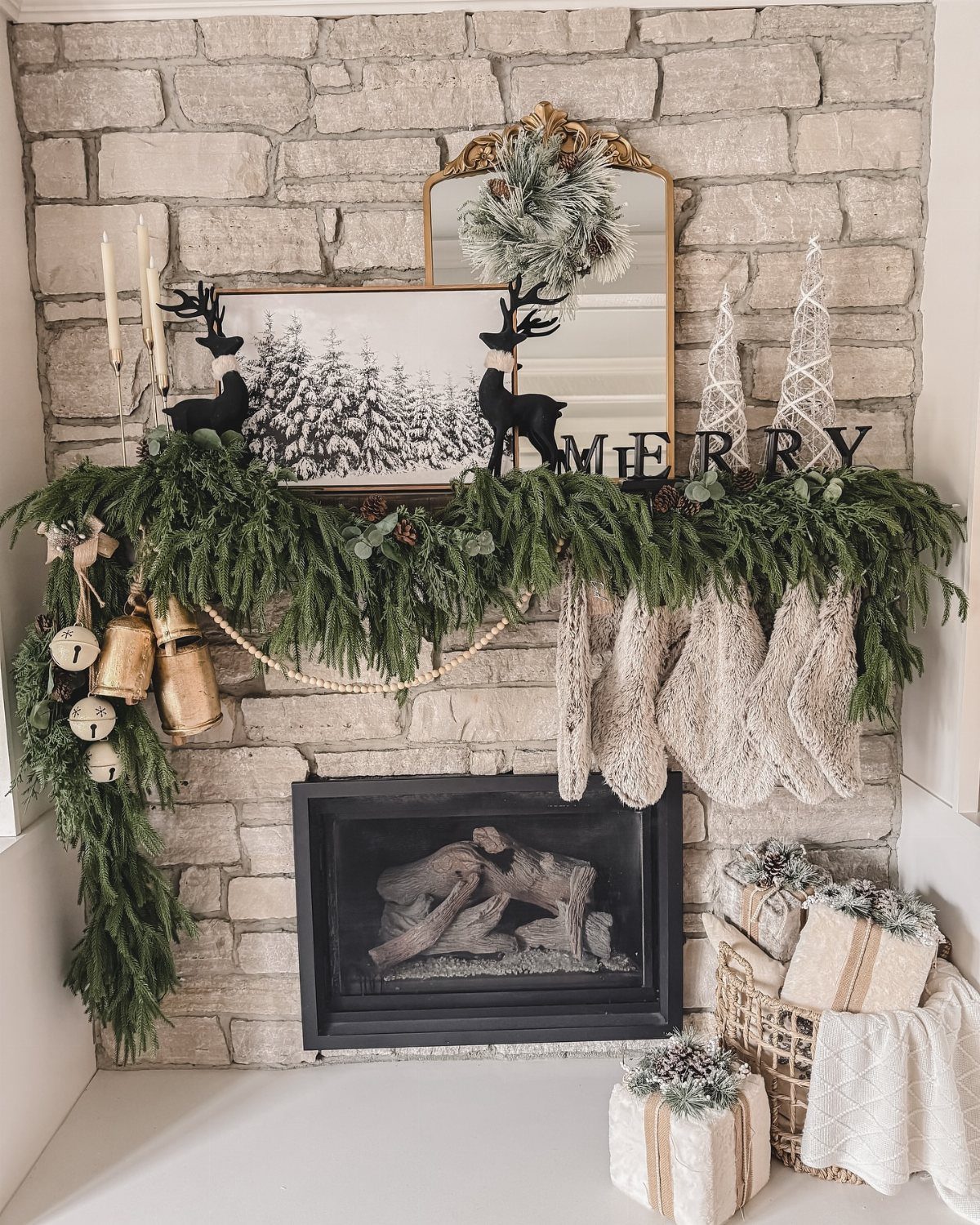 Greenery garland and white stockings decorating a brick fireplace mantel with reindeer silhouettes.