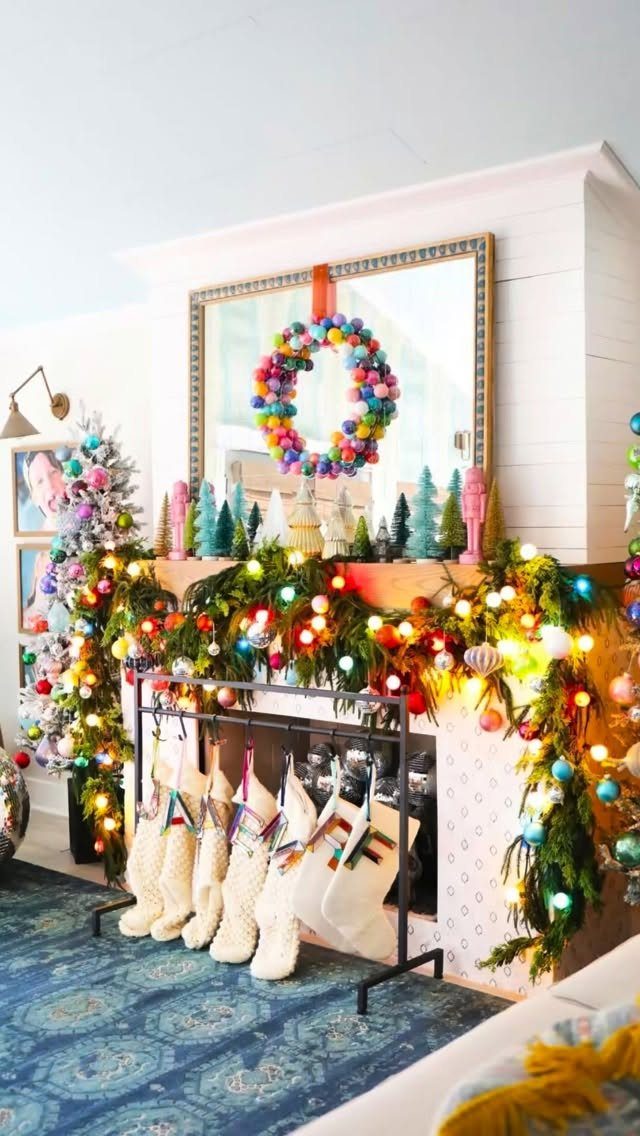 Colorful Christmas ornaments and lights decorating a lush green garland on a white fireplace mantel.