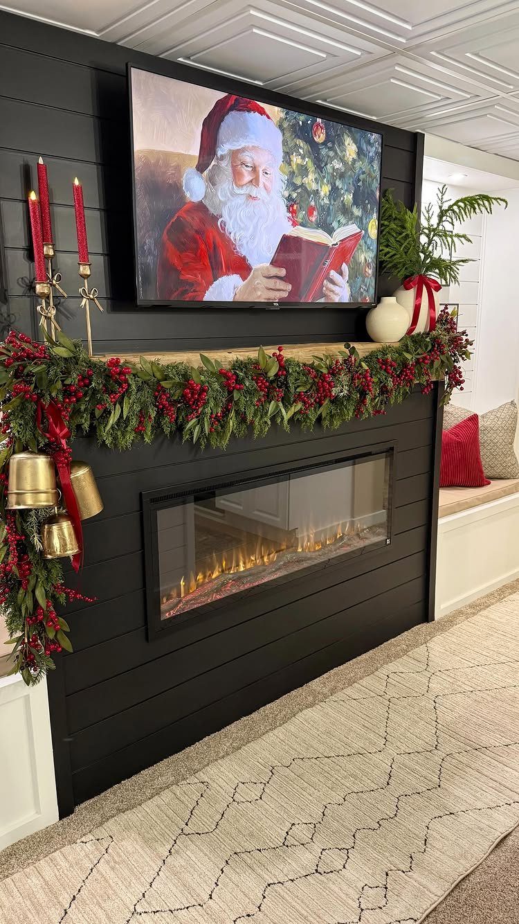 A black fireplace mantel decorated with festive green garland, red berries, and gold bells.