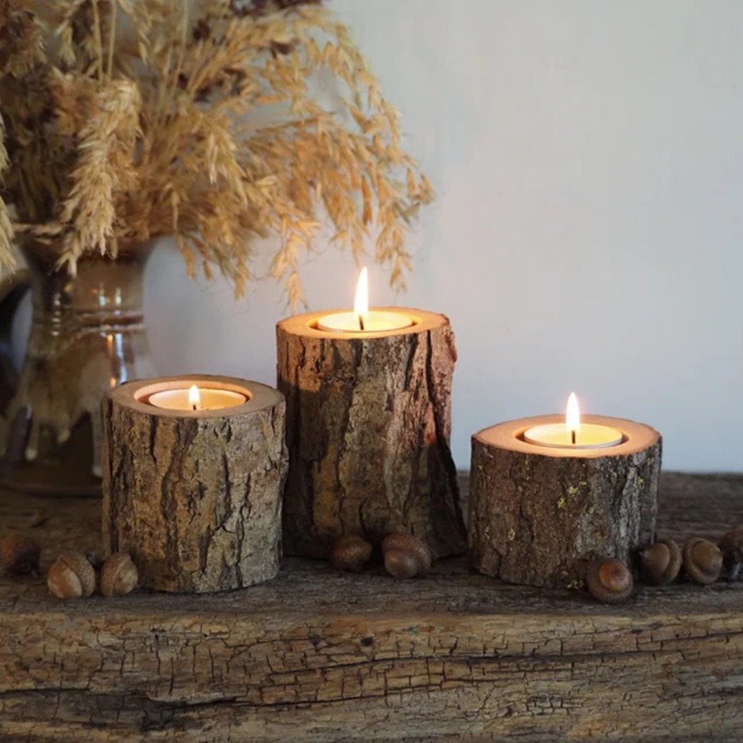 20 Christmas Rustic Decor Ideas for a Warm Holiday Home 4 Three tree bark candle holders with lit tea lights on a rustic wooden table.