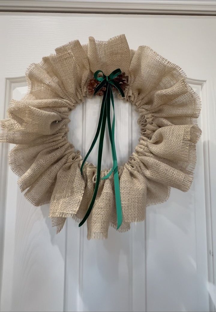 20 Christmas Rustic Decor Ideas for a Warm Holiday Home 3 A burlap ruffled wreath with a green ribbon bow hanging on a white door.