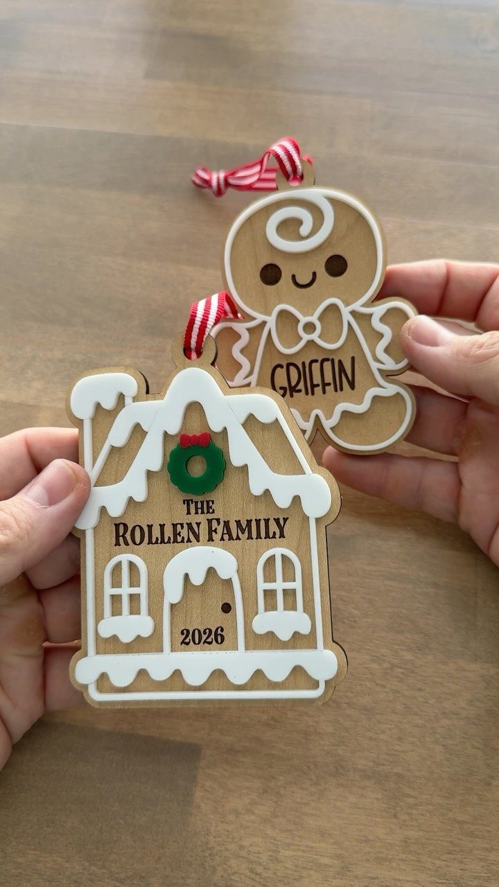 Two wooden gingerbread-themed Christmas ornaments held by hands against a wooden background.