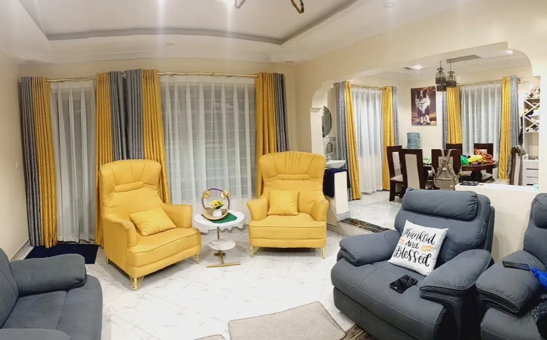 Yellow armchairs and grey sofas arranged in a living room with grey and yellow curtains.