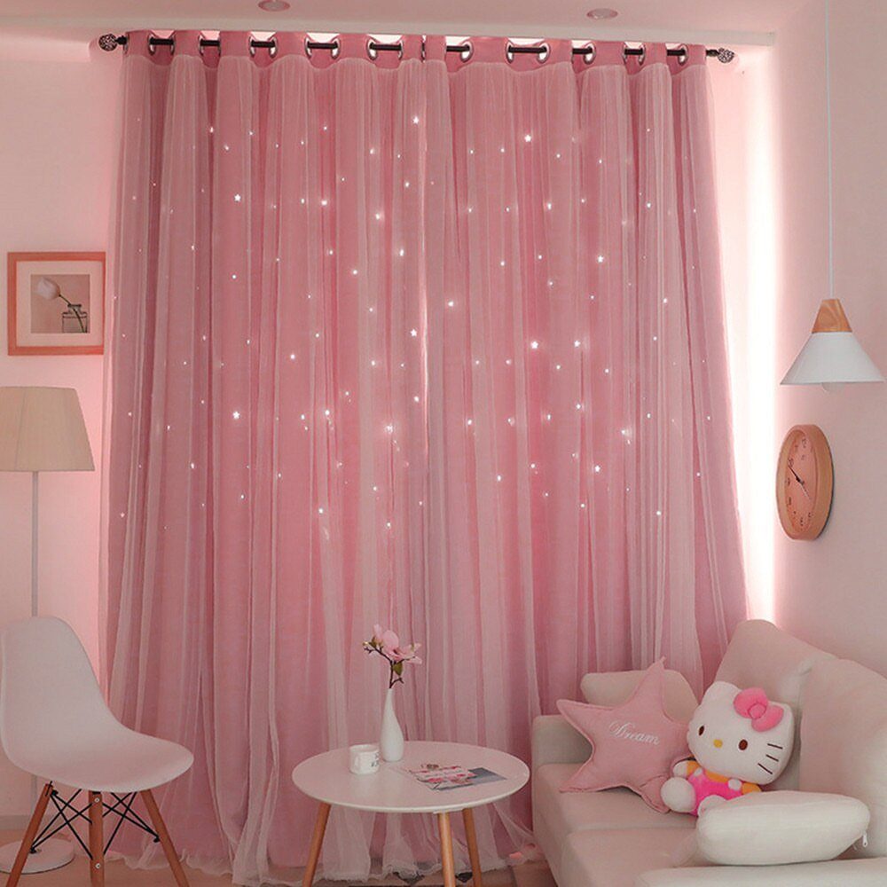 Pink sheer curtains with twinkling lights hanging in a brightly lit room with white furniture.