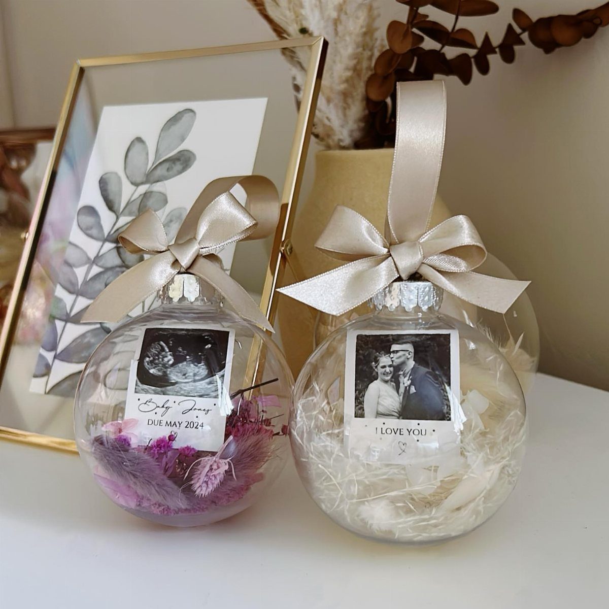 7 Ideas for Decorating Clear Ornaments with Glitter, Crayon & More 5 Two clear glass ornaments decorated with personalized black and white photos and satin bows.