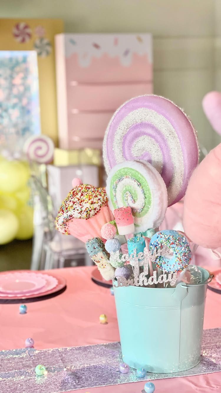 DIY Candyland Decorations: 10 Creative Party Ideas 3 Colorful candy lollipops and sprinkle treats arranged in a light blue bucket on a pink table.