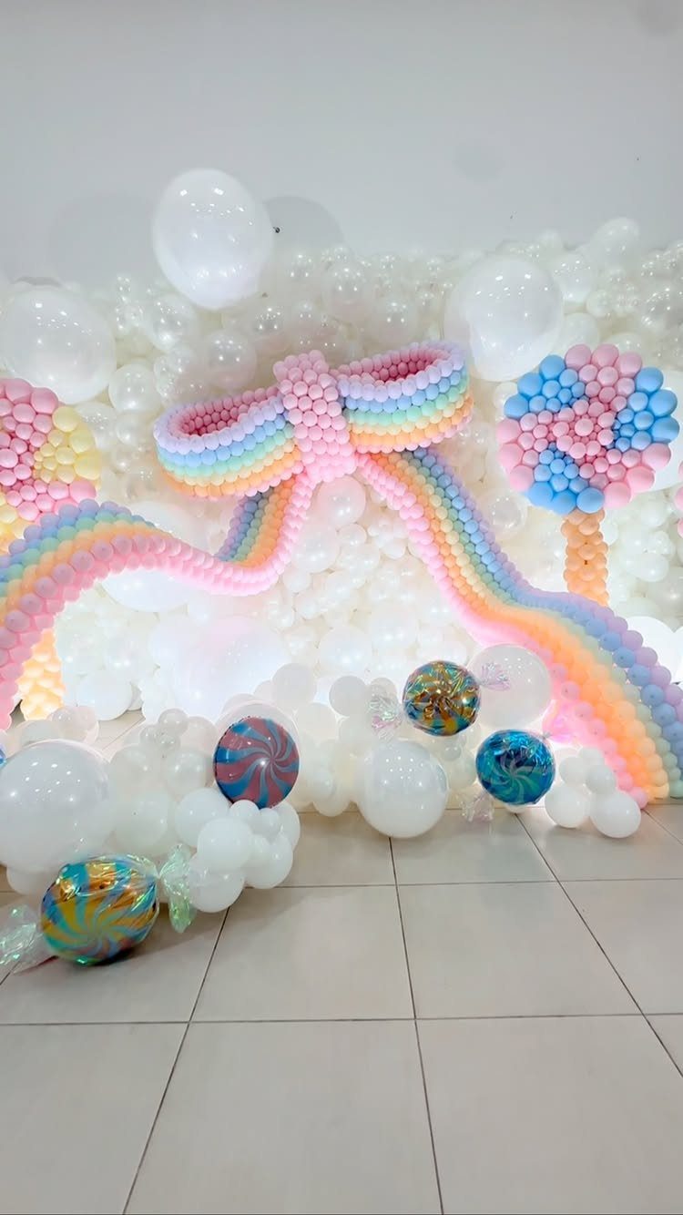 DIY Candyland Decorations: 10 Creative Party Ideas 1 Colorful balloon installation featuring a rainbow bow and a large swirl lollipop prop.