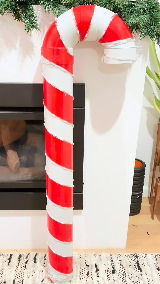 DIY Candyland Decorations: 10 Creative Party Ideas 9 A large red and white striped candy cane decoration standing near a fireplace.