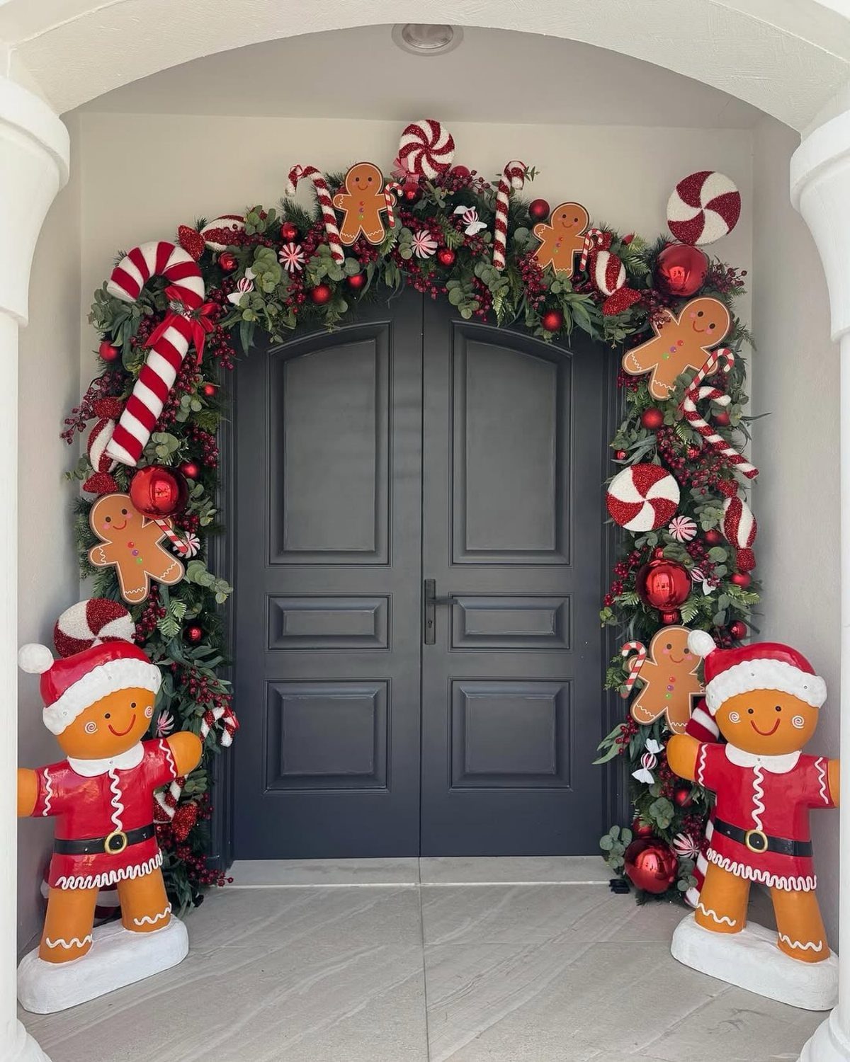 DIY Candyland Decorations: 10 Creative Party Ideas 5 A dark grey double door framed by a festive green garland with gingerbread men and peppermint candies.