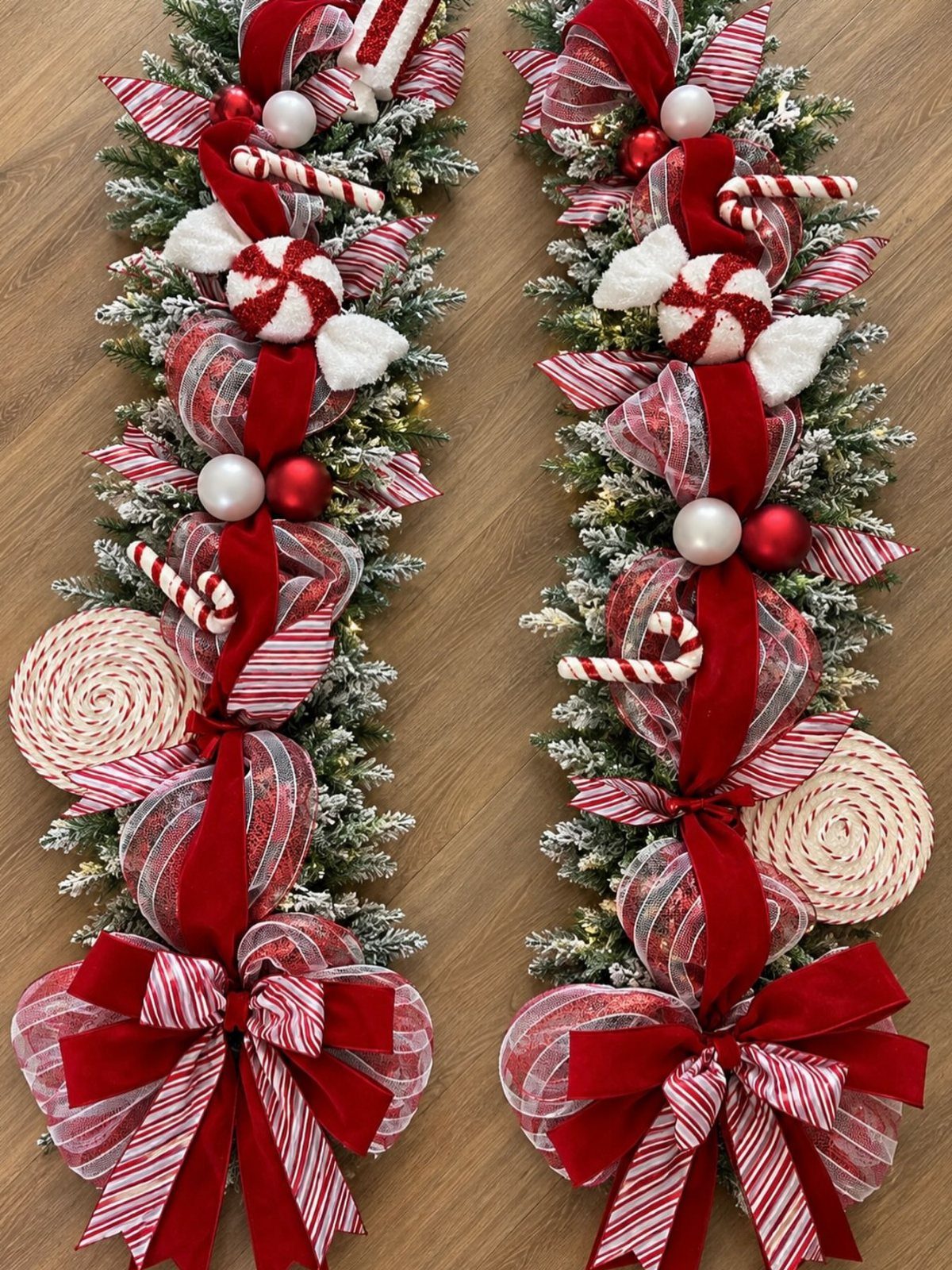 Two festive evergreen garlands decorated with red ribbons, peppermint candies, and ornaments on wood.