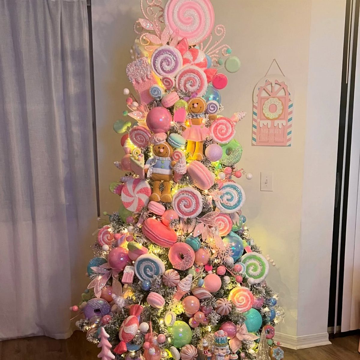 A Christmas tree decorated with large pastel pink, blue, and green candy ornaments.