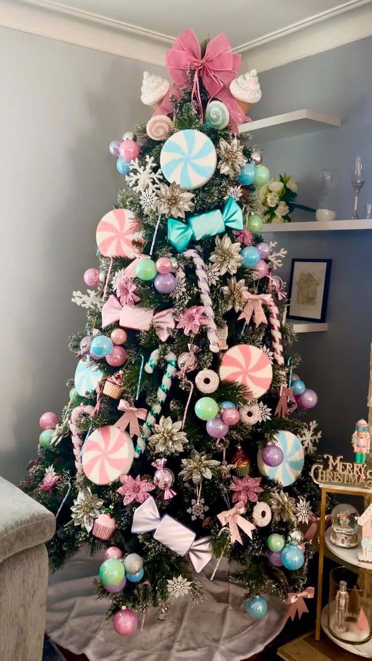 A Christmas tree decorated with pastel pink and mint candy-shaped ornaments and peppermint swirls.