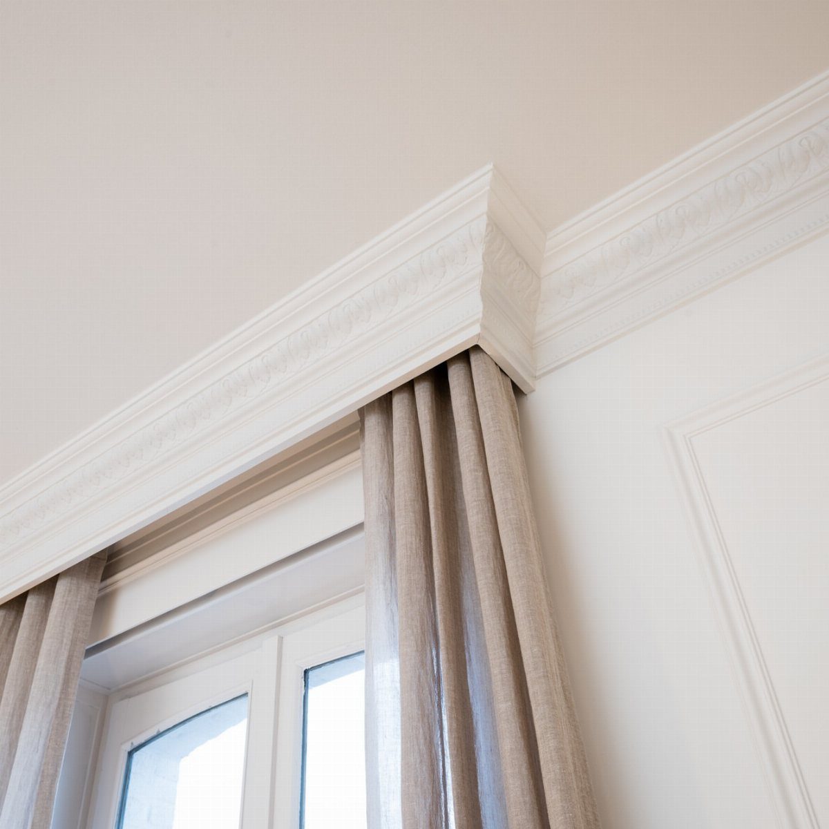 10 DIY Window Covering Ideas for a Quick Upgrade 10 Beige linen curtains hanging from white decorative crown molding above a bright window.