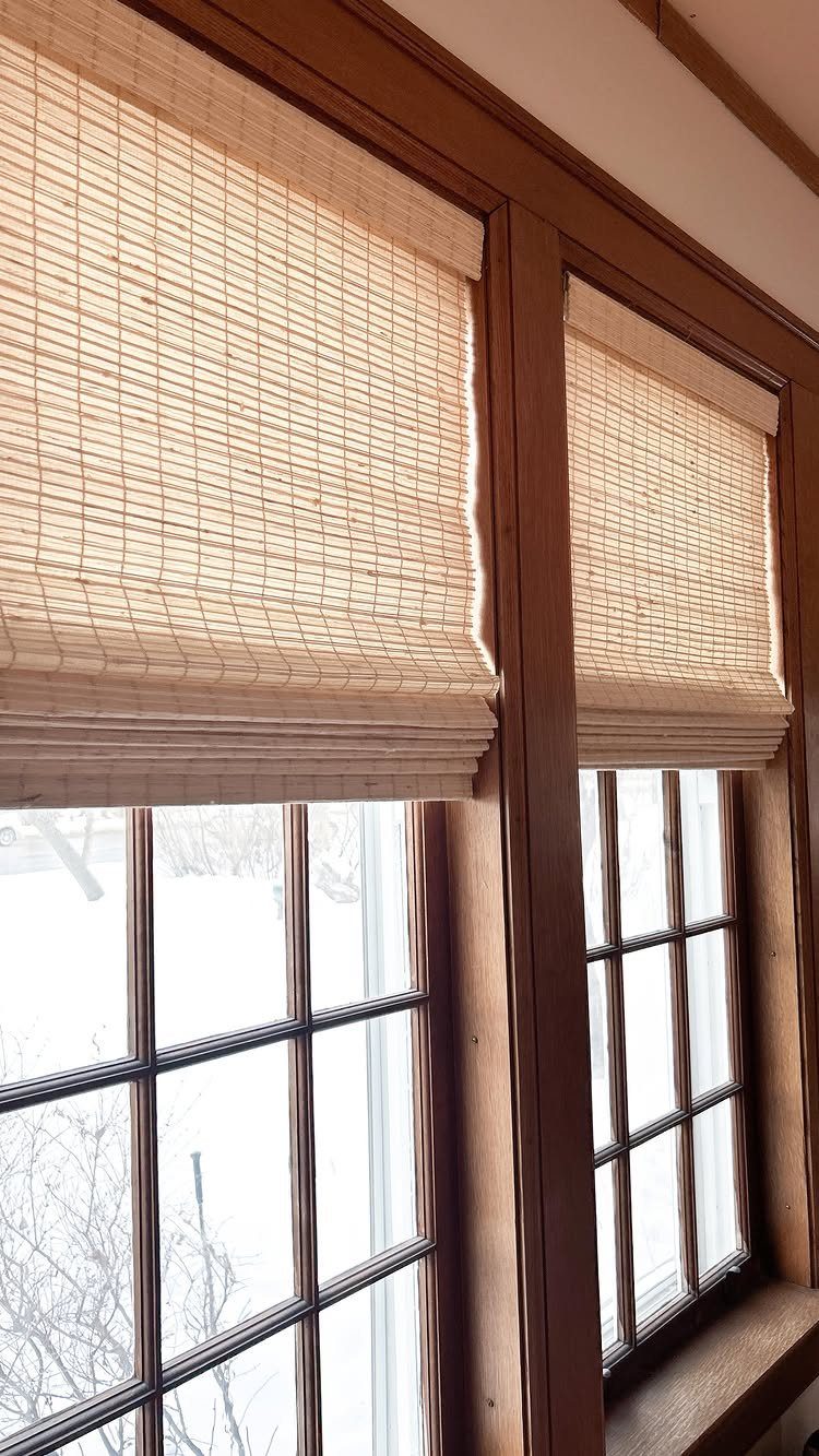 10 DIY Window Covering Ideas for a Quick Upgrade 6 Woven bamboo shades partially covering wooden-framed windows overlooking a snowy outdoor landscape.