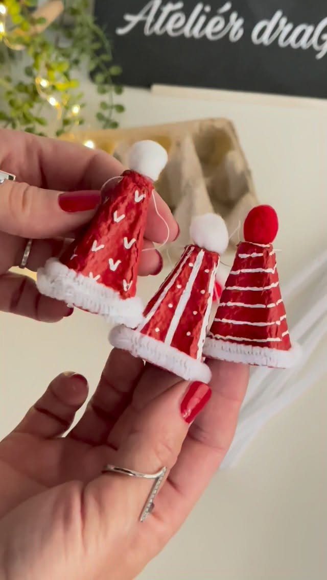 Three red and white cone-shaped egg carton ornaments held in a person's hands.