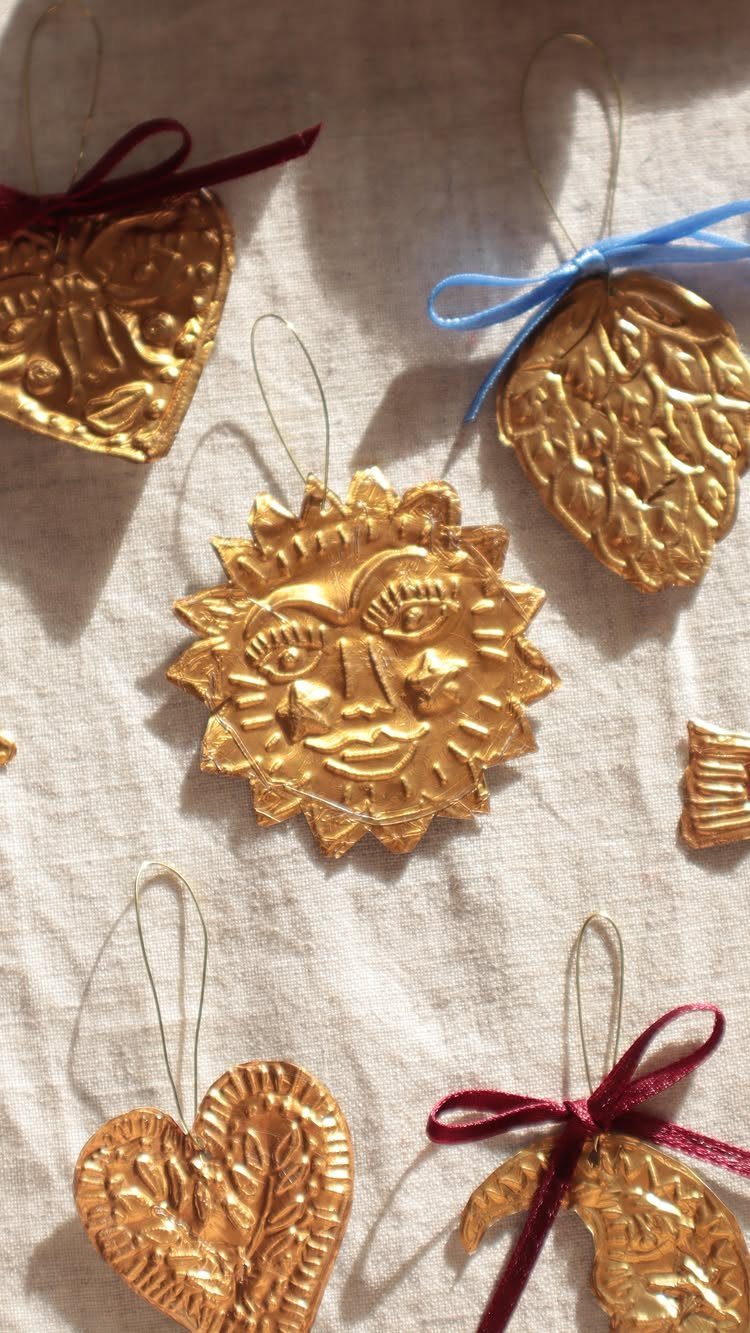 Gold textured sun and heart shaped ornaments resting on a light beige fabric surface.