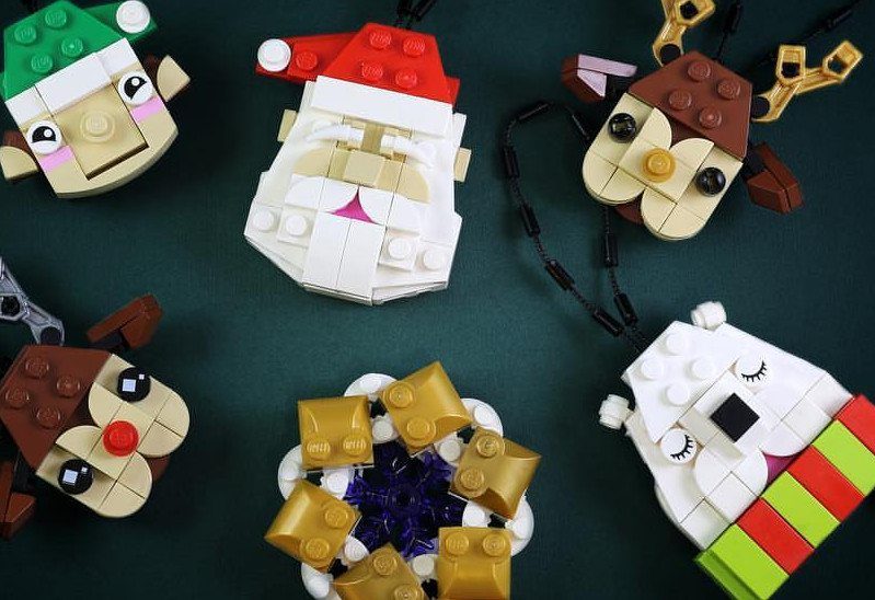Various colorful LEGO bricks assembled into festive Christmas character ornaments on a green background.