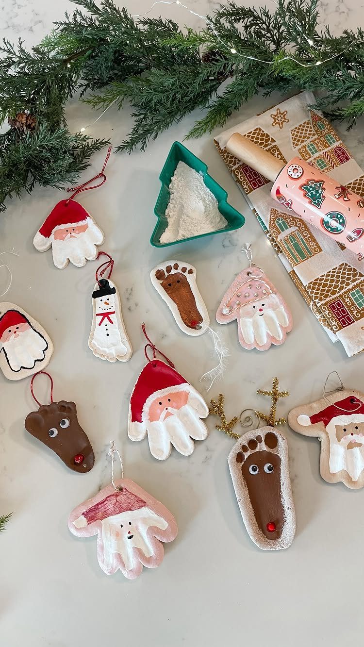 Handmade salt dough Christmas ornaments shaped like Santas, snowmen, and hands on a white surface.
