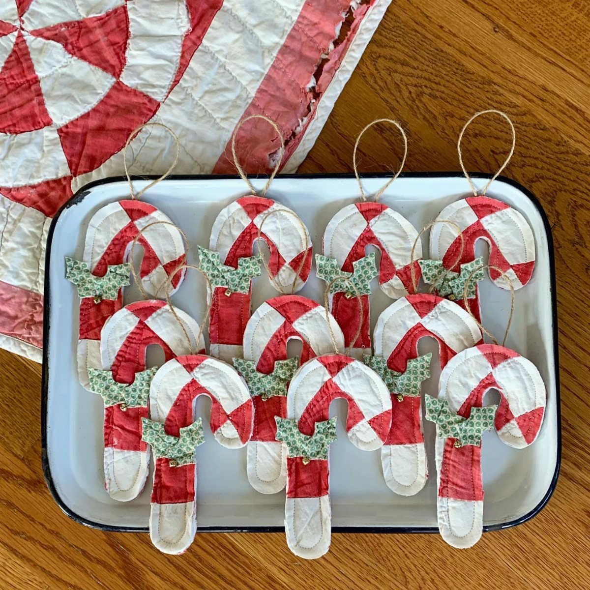 Handmade fabric candy cane ornaments with green bows resting on a white tray.