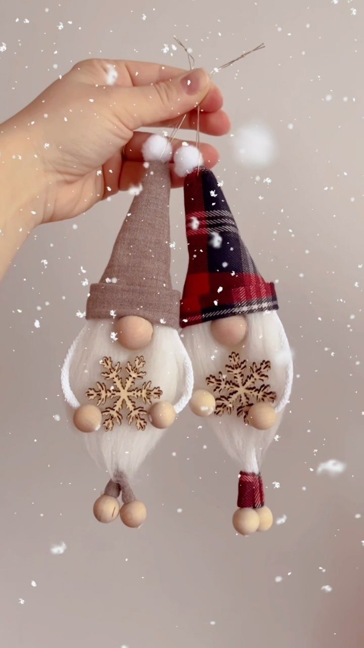 Two handmade fabric gnome ornaments with wooden snowflake accents held by a hand.