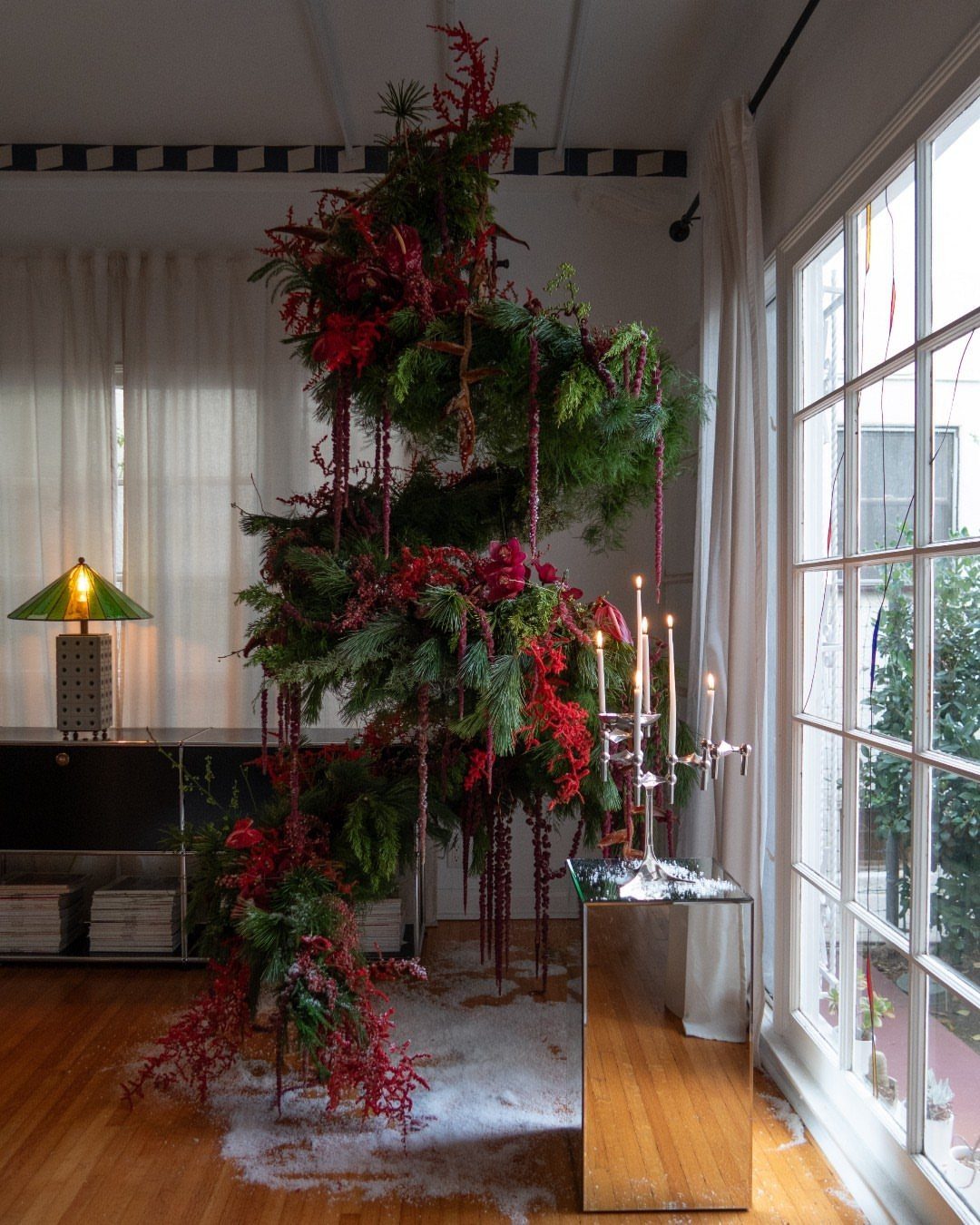 Hanging Christmas Tree: 6 Ideas for Small Spaces 4 A spiral-shaped Christmas tree made of greenery and red flowers hanging in a bright room.
