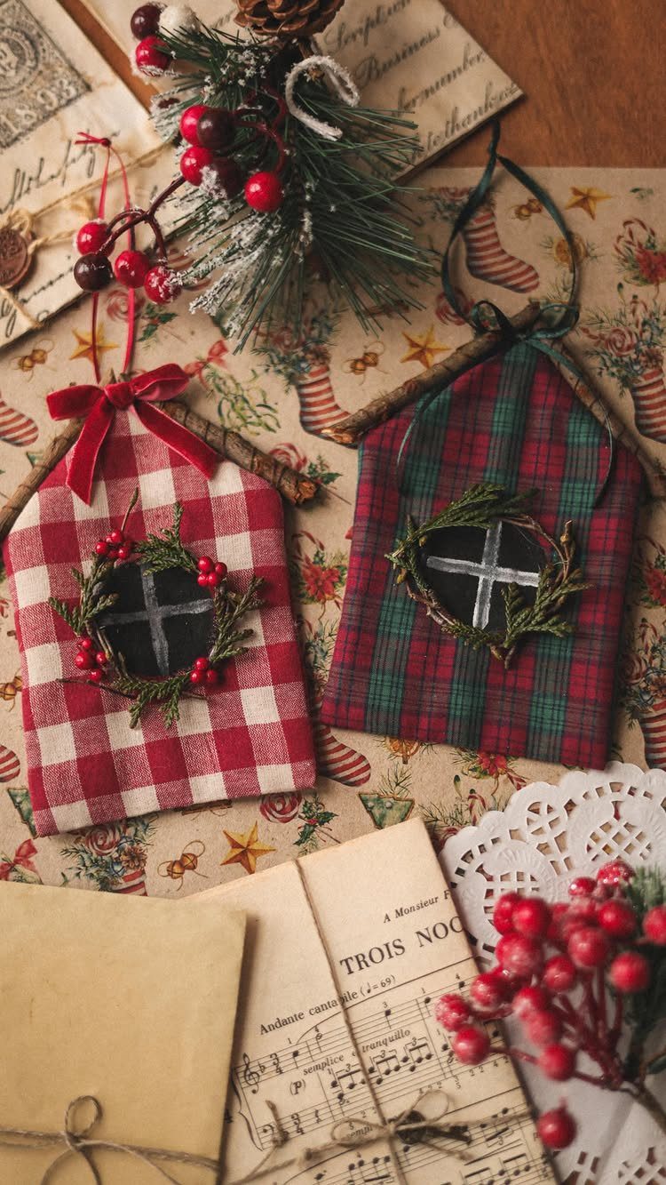 Homemade Christmas Decorations: 17 Easy Projects for 2026 14 Two fabric house ornaments with tiny wreaths resting among pine sprigs and red berries.
