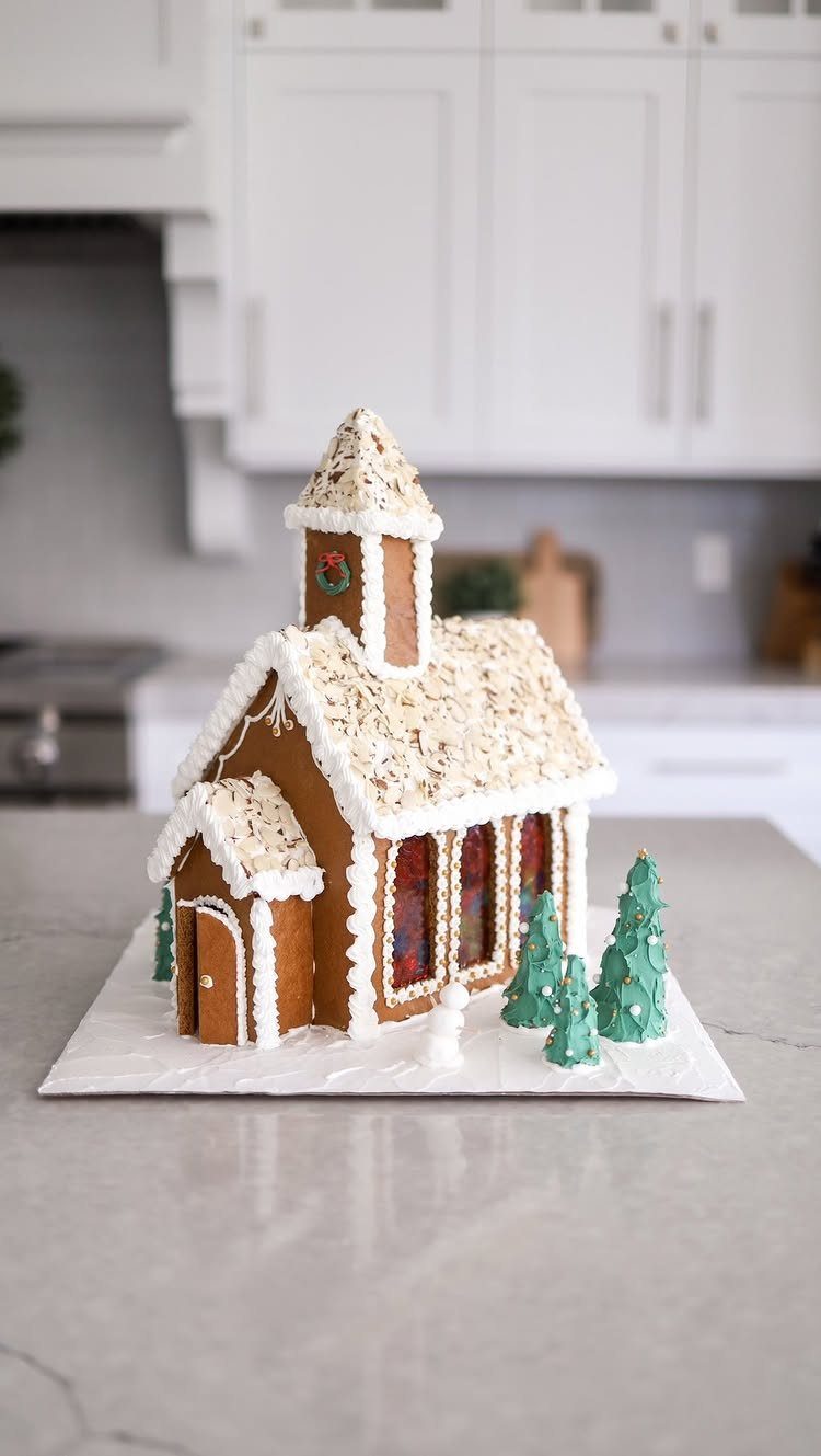Homemade Christmas Decorations: 17 Easy Projects for 2026 15 A decorated gingerbread church with white icing snow and small green icing trees on a counter.