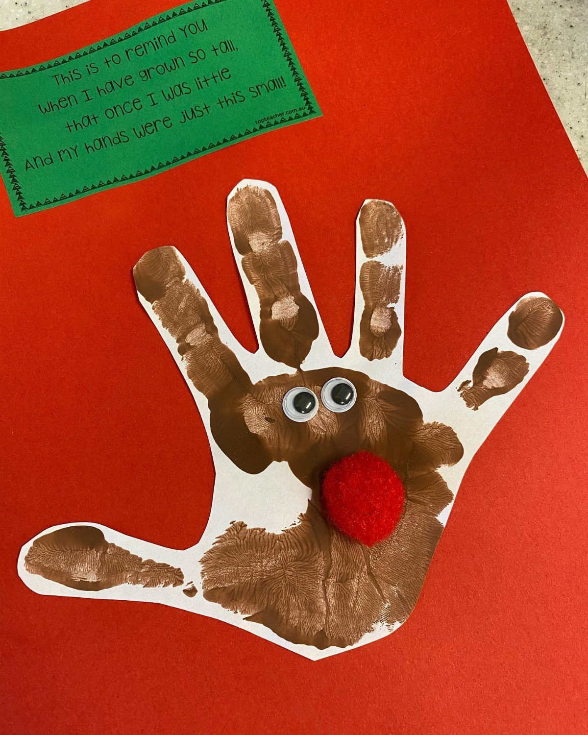 Homemade Christmas Decorations: 17 Easy Projects for 2026 7 A brown handprint reindeer craft with googly eyes and a red pom-pom nose on red paper.