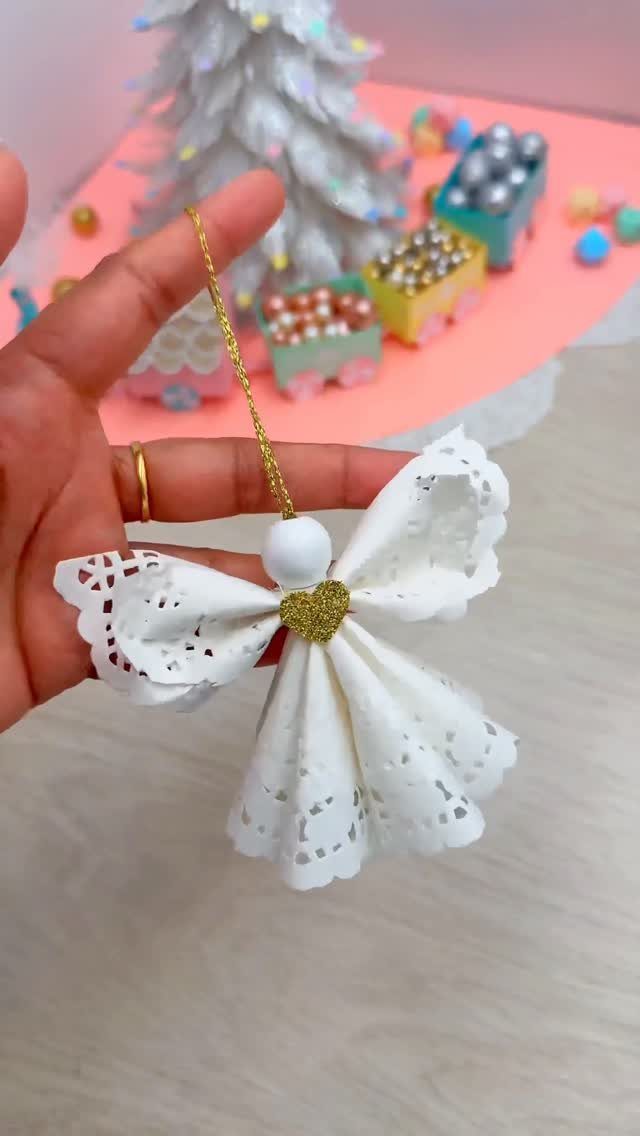 Homemade Christmas Decorations: 17 Easy Projects for 2026 12 A hand holding a white lace angel ornament with a gold glitter heart decoration.