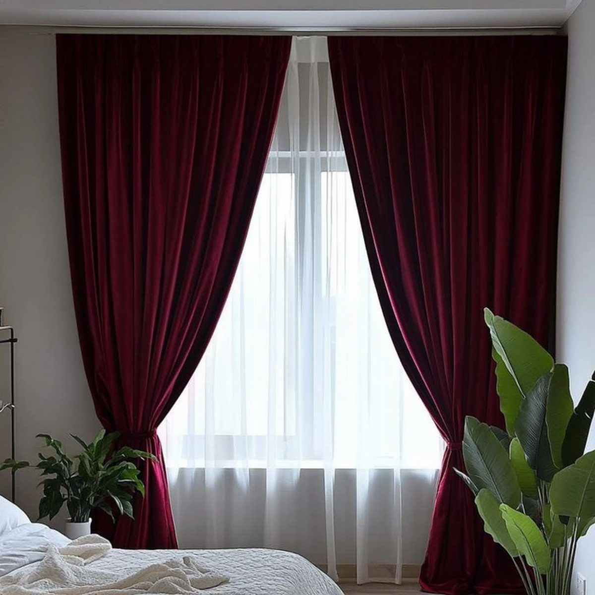 13 House Curtains Ideas for Every Style 8 Deep red velvet curtains draped over a window with white sheer curtains and green plants.