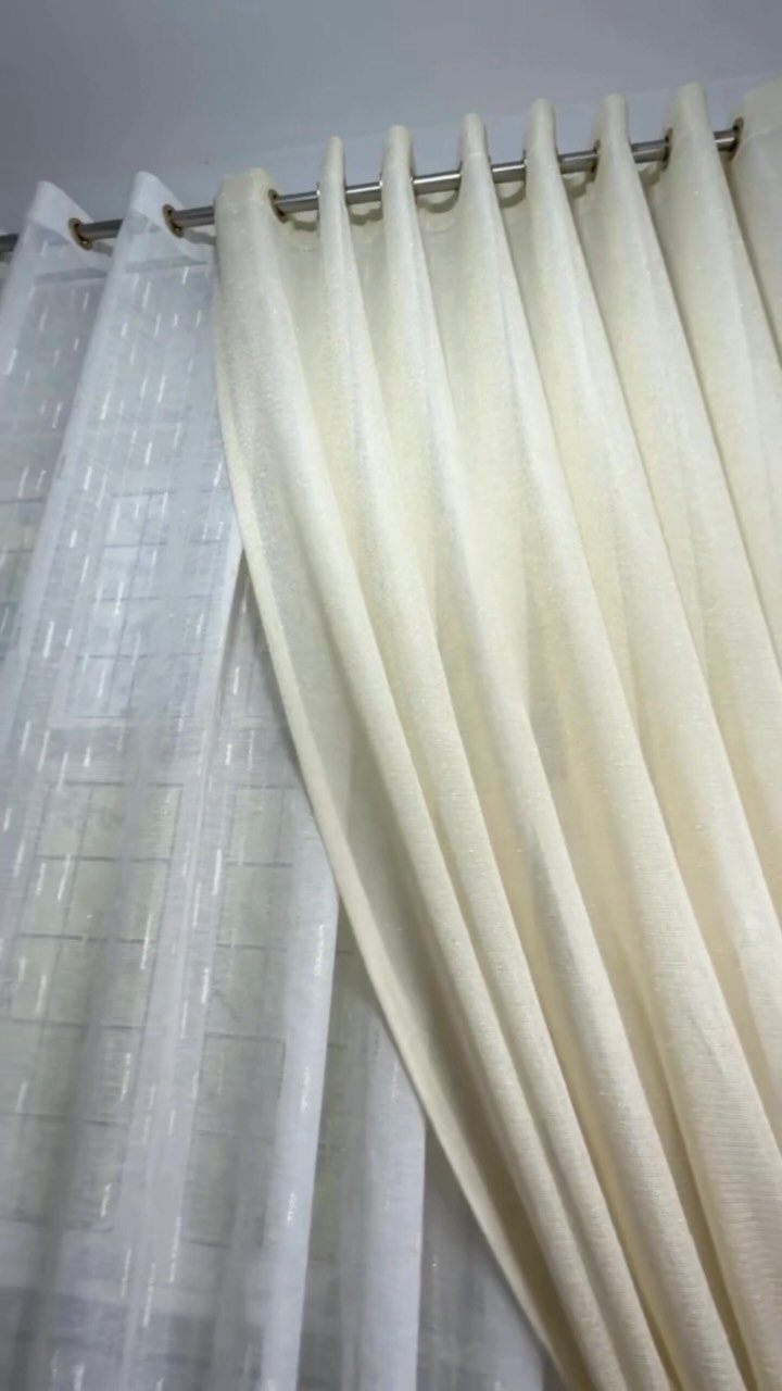 13 House Curtains Ideas for Every Style 5 Cream fabric curtains hanging from a silver metal rod via large metal grommets.