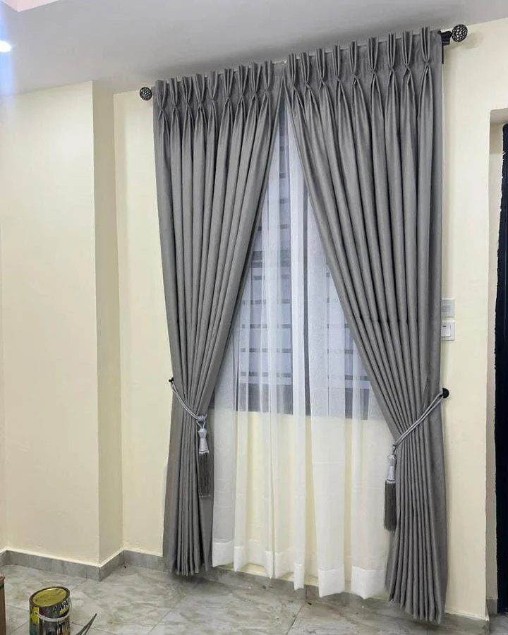 13 House Curtains Ideas for Every Style 3 Two grey curtain panels tied back with cords over white sheer curtains on a window.