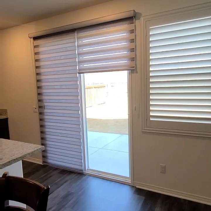 Striped horizontal shades covering a sliding glass patio door and a side window in a room.