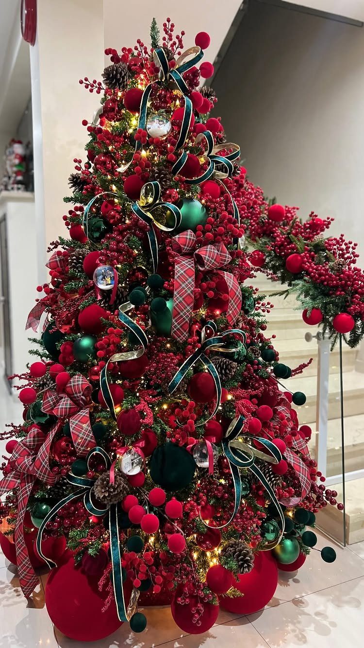 A Christmas tree decorated with red berries, green baubles, and red plaid ribbons.