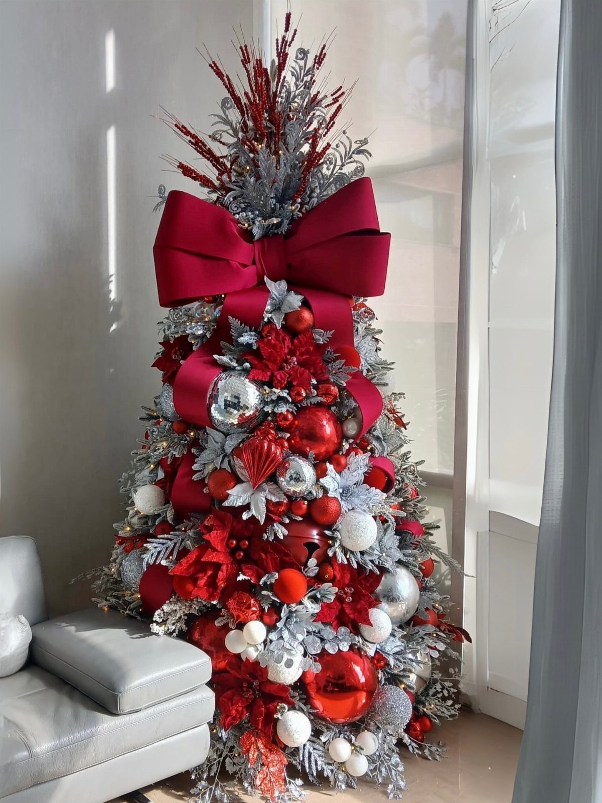Decorated silver Christmas tree with large red bows and red and silver ornaments.